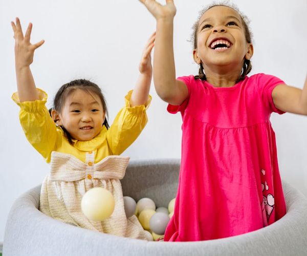 Group of diverse children laughing and playing together in a bright room.
